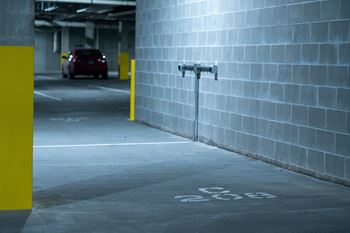 A parking garage with a red car and a yellow pole.